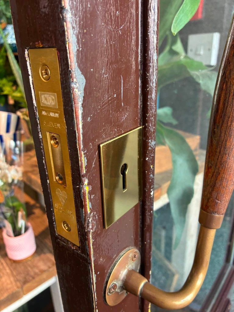 Polished brass keyhole escutcheon plate and Union deadlock installed on a commercial wooden door by ASL Locksmiths in Brighton.