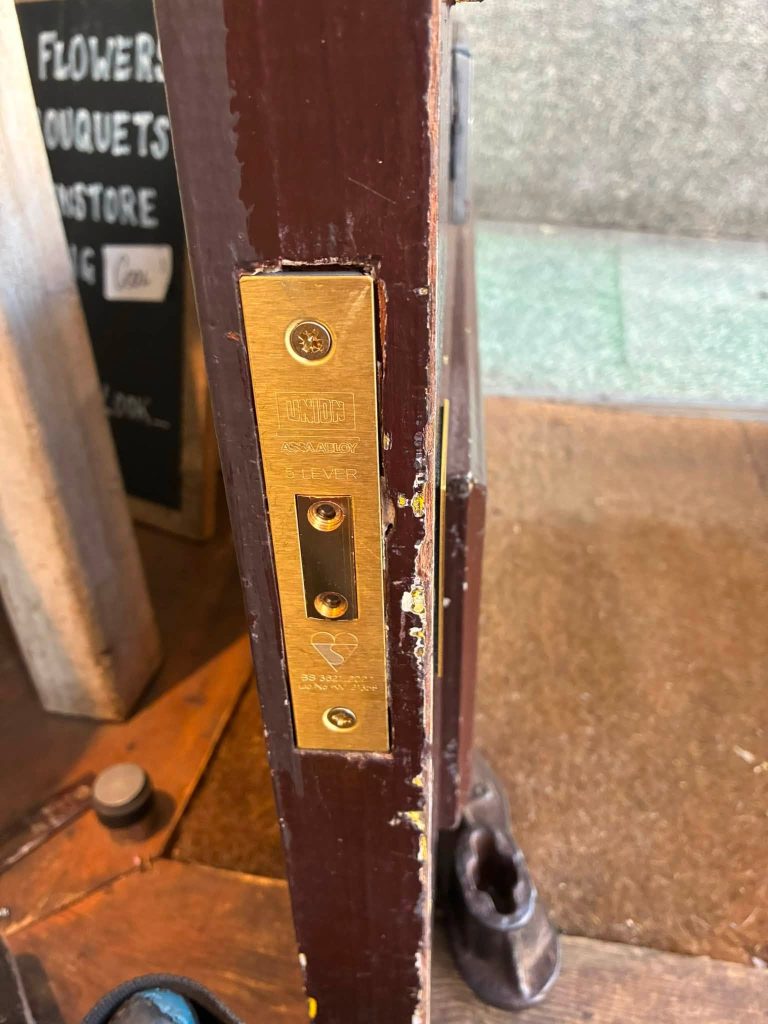 A newly fitted Union 5-lever British Standard brass deadlock installed into the edge of a commercial wooden door.